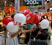 Hostessa rozdaje balony z nadrukiem pozakładane na patyczki.