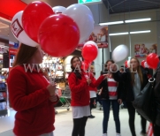 Hostessy rozdają balony na patyczkach.